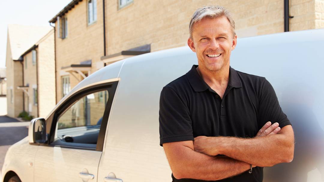 Income Protection for the Self-Employed. Image of self-employed tradesman standing besides his work white van.