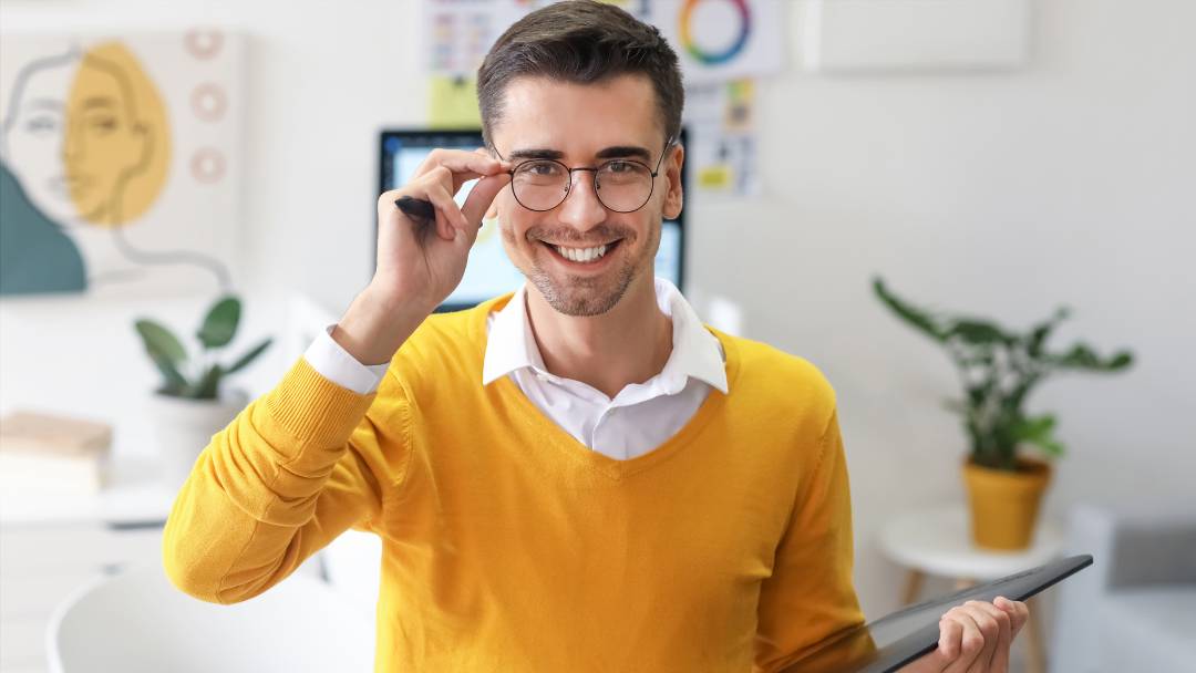 Protect Your Income as a Freelancer. Man in his 30s standing holding his Tablet in his studio as a Freelance designer.